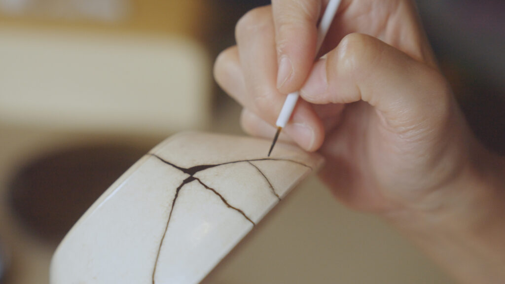 Frau repariert gebrochene Schale. Kintsugi.